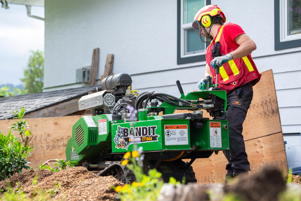 Man in hi-viz using stump grinder